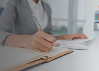 Woman using her computer and writing on a notebook