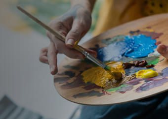 Painter mixing colors on a color palette with a brush