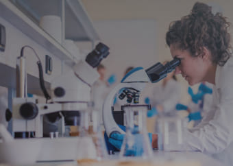 Scientist in a lab looking through a microscope