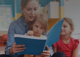 Teacher reading a book to two students