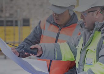 Two engineers with hardhats looking at a blueprint