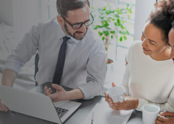 A bisinessman using his laptop while talking to two clients 