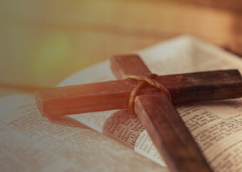 Wooden cross on top of an open Bible