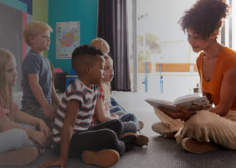 Teacher reading a book to a group of children in a class room